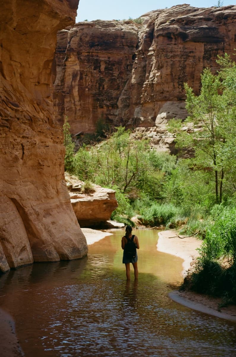 One person standing alone in a quiet canyon stream